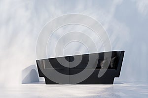 Black sofa in empty room with white wall. Lights and shadows