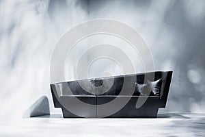 Black sofa in empty room with white wall. Lights and shadows