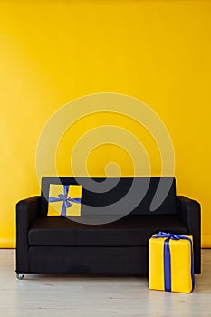 Black sofa with gifts in the interior of the yellow room