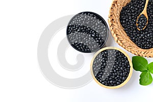 Black soy bean seeds in a bowl and basket with spoon on white background