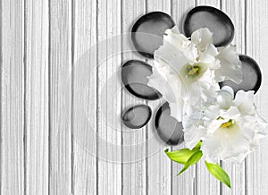 Black spa stones with flower on white wooden background