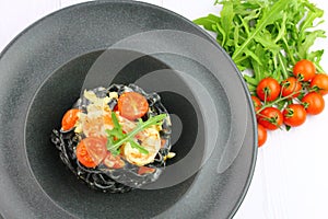 Black spaghetti. Black seafood pasta in white plate on black background with copy space.