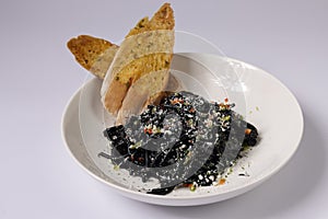 Black spaghetti pasta negra iwith garlic bread in a dish top view on grey background singapore food photo
