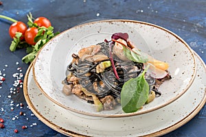 Black spaghetti with prawns and mussels seafood pasta on white plate on blue background