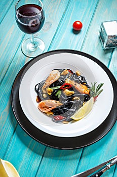 Black spaghetti. Seafood pasta with mussels and prawns over blue wooden background