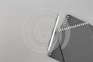 Black spiral notepad with white pencile.