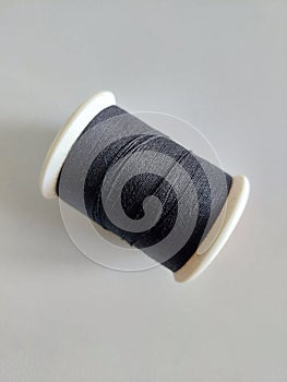 Black spool of sewing thread on white table. photo