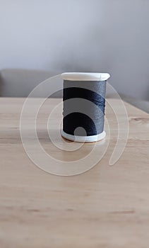 Black spool of sewing thread on wooden table. photo