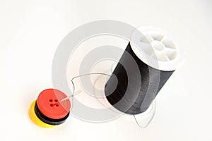Black spool of thread, needle and buttons