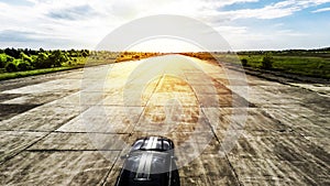 Black sports car on abandoned runway ready to race