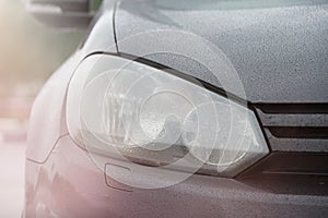 Black sports car front light after the rain with lens flare coseup