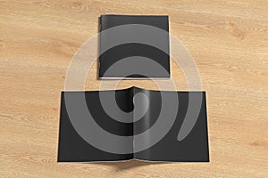 Black square brochure or booklet cover mock up on wooden background. Closed one brochure and upside down other.