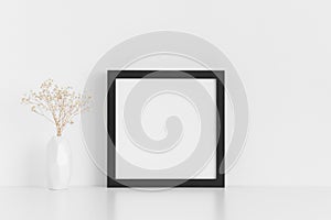 Black square frame mockup with a gypsophila in a vase on a white table
