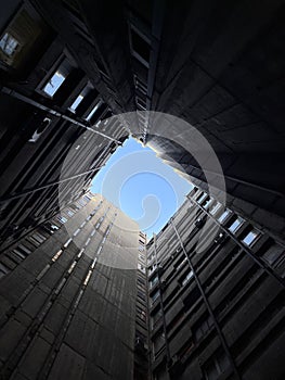 a black square in between some tall building with windows in it photo
