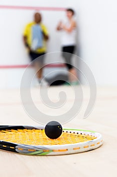 Black squash ball on rackat close up foreground focus.