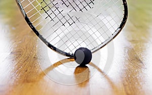 Black squash ball and tennis racket in tennis club