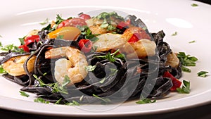 Black squid ink Fettuccine pasta with prawns or shrimps cherry tomatoes, parsley, chili in wine and butter sauce. Zoom in shot