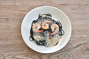 black squid ink spaghetti with shrimp dressing white carbonara cream sauce on plate