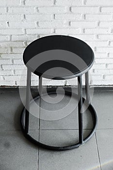 Black stainless stool in front of brick wall