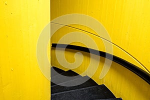 Black staircase with yellw wall background and black bannister