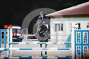 Black stallion horse and handsome man rider jumping obstacle