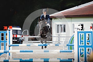 Black stallion horse and handsome man rider jumping obstacle