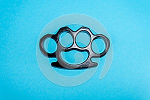 Black Steel brass knuckles blue background hooligan fight, fighting without rules, street banditry, injuries