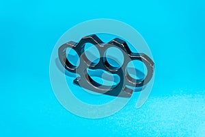 Black Steel brass knuckles blue background hooligan fight, fighting without rules, street banditry, injuries