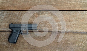 Black steel polymer semi-automatic 9mm pistol on wooden background with Copy Space.