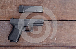Black Steel semi-automatic 9mm pistol and magazine on wooden background with Copy Space