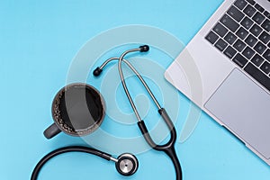black stethoscope, laptop, coffee, blue  background