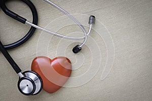 Black stethoscope with red heart of doctor for check up on beige background.