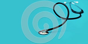 Black stethoscope in shallow depth-of-field on blue background