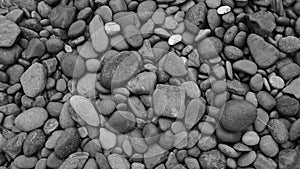 Black stone background. Shiny black lava pebbles on the beach