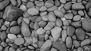 Black stone background. Shiny black lava pebbles on the beach