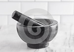 Black Stone Mortar and Pestle on a Marble Countertop