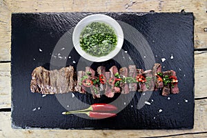 Black stone plate with skirt steak pepper and chimichurri sauce