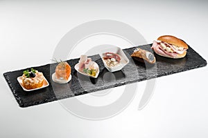 Black stone rectangular tray with shrimp tartare snack cannoli swordfish ravioli with robbiola tartina nordica mousse aubergine photo