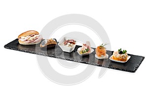 Black stone rectangular tray with shrimp tartare snack cannoli swordfish ravioli with robbiola tartina nordica mousse aubergine photo