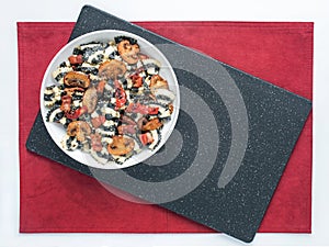 Black Striped Pasta with Mushrooms and Tomatoes on Black and Red