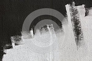 Black strokes of paint roller on white textured stucco wall