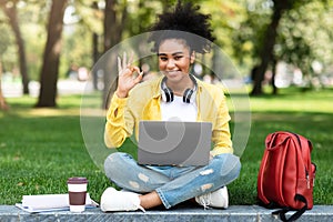 Black Student Girl Using Laptop Gesturing OK Symbol Sitting Outdoor