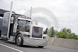 Black stylish classic big rig semi truck running on road