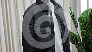 Black stylish pants and a fashionable jacket on a white mannequin in a clothing store. Sale of branded clothing. Slow