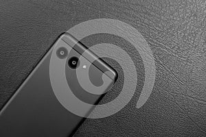 Black stylish smartphone on dark leather background