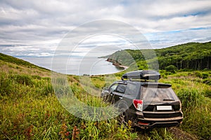 Black Subaru Forester with rooftop box on the road way down to the sea