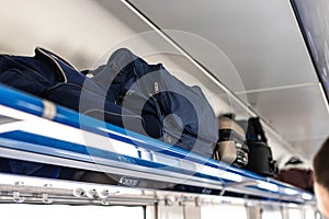 Black suitcase on the shelf in the train car. Holiday vacation, tourism, travel, modern train interior, of railway transportation