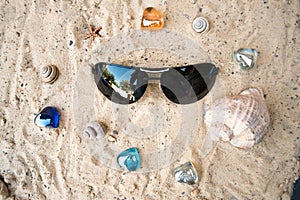 Black sunglasses on the beach in the sand.