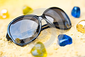 Black sunglasses on the beach in the sand.