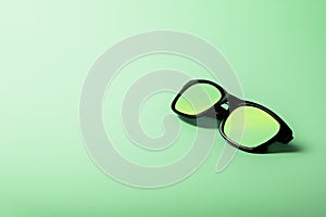 Black sunglasses with Multicolor Mirror Lens on green background. Polarized sunglasses with UV protection.